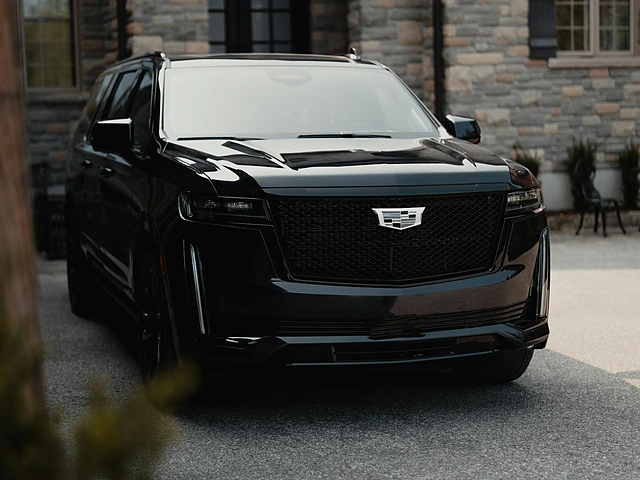 A black SUV parked in the driveway of a stone house