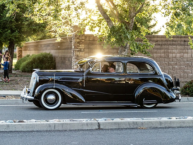 A restored black classic car cruising in evening light