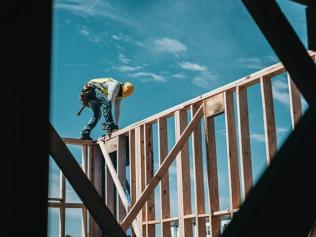 A framer working on the top of a wood-framed wall